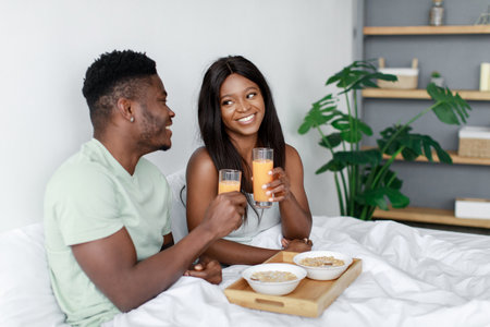 Couple Enjoys a Cozy Breakfast in Bed With Smoothies and Oatmeal in a Modern, Relaxed Room Settingの写真素材