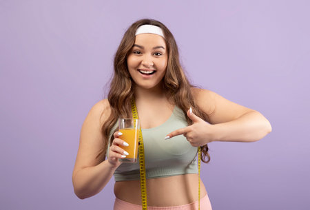Smiling Plus Size Lady in Sportswear Celebrates Healthy Choices With Orange Juiceの写真素材