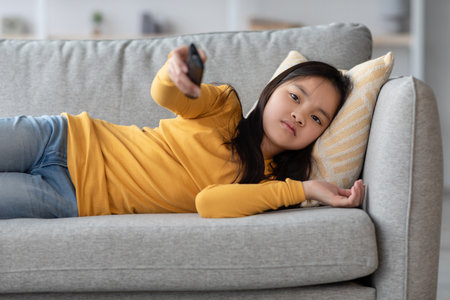 Young Girl Relaxing on a Couch While Watching TV in a Cozy Living Room Settingの写真素材