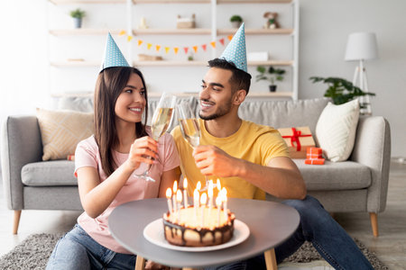 Couple Celebrating Birthday at Home With Cake and Champagne in Cozy Settingの写真素材