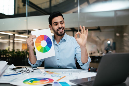 Creative Professional Shares Color Wheel While Reviewing Design Plans in Modern Workspaceの写真素材