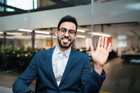 Professional Man Waving in Modern Office Setting During Business Interaction