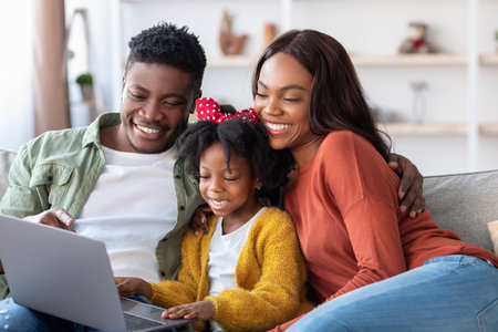 Family Enjoying Quality Time Together While Using a Laptop in a Cozy Living Room Settingの写真素材
