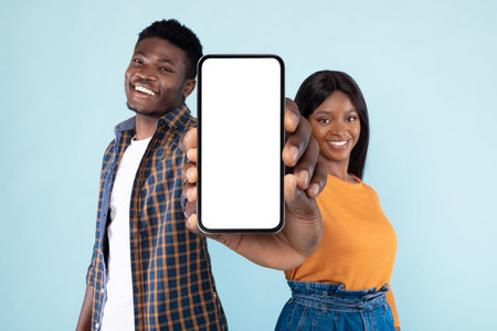 Happy Black Couple Showcases Mockup Smartphone Screens Against Blue Background