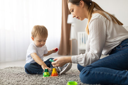 Playing With Colorful Stacking Toys in a Cozy Indoor Space With a Mother and Her Childの写真素材
