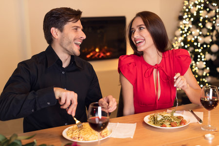 Couple Enjoying a Romantic Dinner With Pasta and Wine by a Cozy Fireplace During the Holiday Seasonの写真素材