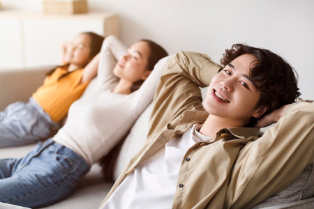 Group of Friends Relaxing Together on a Couch in a Cozy Living Room Enjoying Quality Time on a Weekend Afternoonの写真素材