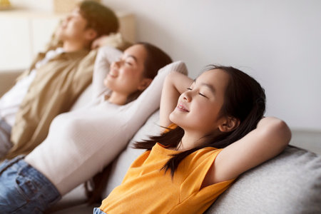 Family Enjoys Relaxing Moment Together at Home on a Cozy Sofa in the Afternoon Lightの写真素材