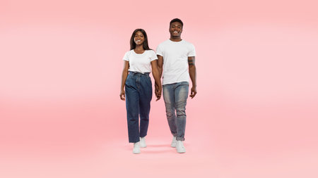 Confident Couple Walking Hand in Hand in Front of a Pink Studio Background