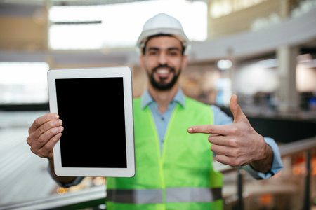 Construction Worker Shows Tablet While Smiling at a Work Site in Bright Green Vest
