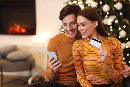 Couple Enjoying Online Shopping Together by a Cozy Fireplace During the Holiday Seasonの写真素材