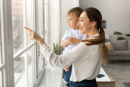 Mother and Child Enjoying a Moment Together by the Window in a Bright Living Roomの写真素材