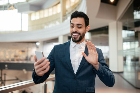 Businessman Engaging in a Virtual Meeting While Standing in a Modern Office Settingの写真素材