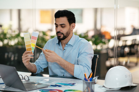 Man Selecting Paint Colors at a Modern Workspace While Planning a Design Projectの写真素材
