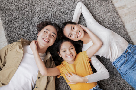 Smiling Family Enjoying Time Together Indoors on a Soft Rug in a Cozy Living Room Settingの写真素材
