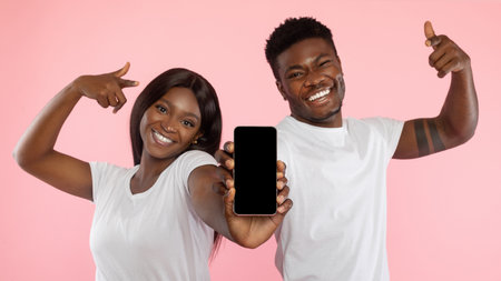Cheerful Couple Showcases Smartphone for New App Recommendation in Bright Studio Settingの写真素材