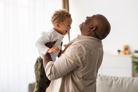 Joyful Grandfather Lifting Grandson at Home During Playful Weekend Moments Togetherの写真素材