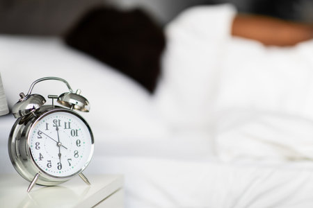 Alarm Clock Shows 6 A.m. as a Woman Sleeps Peacefully in Her Bed in the Morningの写真素材