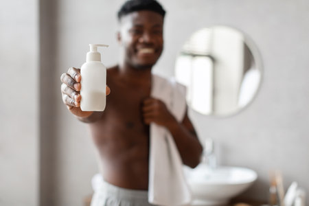 Unrecognizable Man Displays Liquid Soap Bottle in Modern Bathroomの写真素材