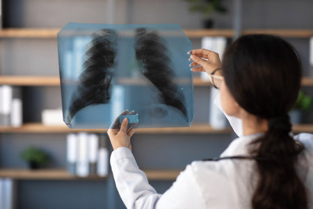 Young Indian Woman Doctor Examines Lung X-Ray in Modern Clinic Settingの写真素材