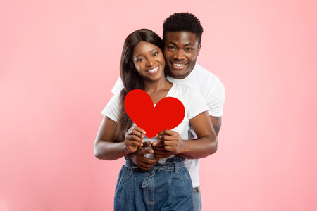 Young Romantic Couple Celebrates Love With Heart on Valentines Day in Pink Studio Background