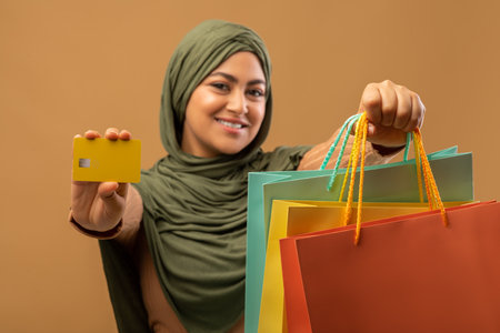 Unlimited shopping concept. Excited arab woman holding colorful shopper bags with gifts and showing...