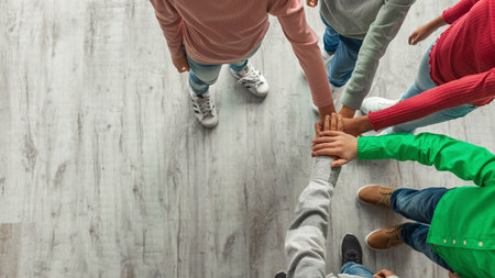 Kids Collaborating on Team Spirit With Hands Stacked Together Indoors From Above Viewの写真素材