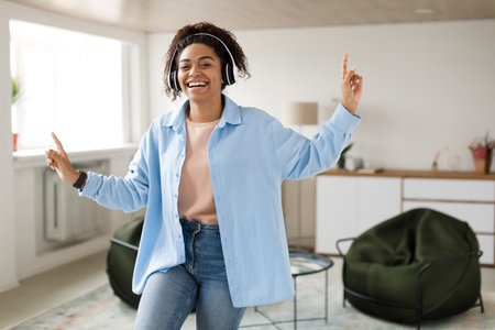 Young Woman Dancing Joyfully Indoors in a Cozy Living Room During the Afternoonの写真素材