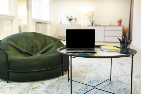 Cozy Workspace Featuring a Green Bean Bag and a Laptop on a Round Table in a Bright, Modern Roomの写真素材