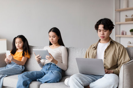 Group of Young People Engaged With Devices While Sitting on a Couch in a Calm Indoor Settingの写真素材