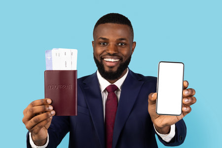 Business Ad. Black Businessman Holding Passport With Ticjets And Showing Blank Smartphoneの写真素材
