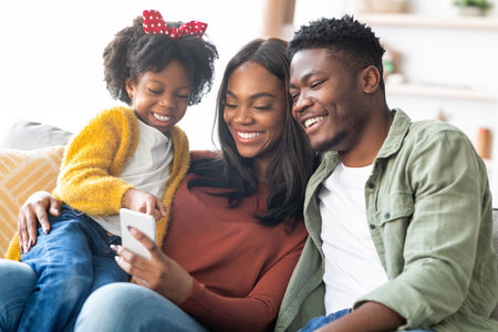 Family Enjoying Time Together While Looking at a Smartphone in a Cozy Living Room During the Dayの写真素材
