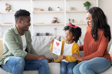 Happy Family Enjoys Quality Time Together at Home While Celebrating a Special Occasion With Handmade Cardの写真素材