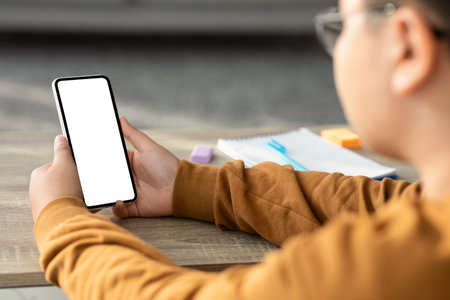 Chubby Boy Using Smartphone During Homework in Cozy Home Settingの写真素材