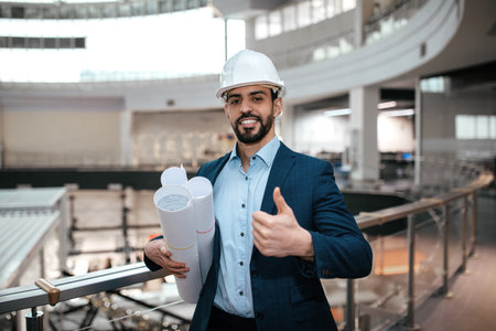 Construction Professional With Plans Gives a Thumbs up in a Modern Building During Daytimeの写真素材