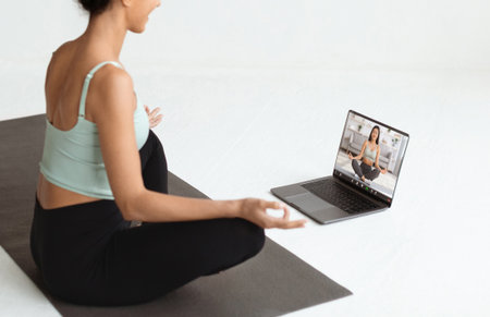 Brunette Woman Meditates During Virtual Yoga Class With Remote Instructor on a Fitness Matの写真素材