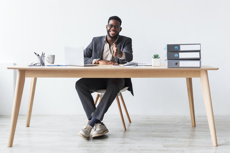 Young Black Businessman Smiles While Offering Handshake in Modern Office Settingの写真素材