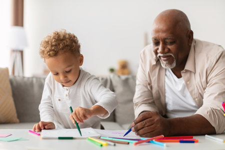 Grandpa and Grandson Enjoying a Colorful Drawing Session Together Indoors During the Weekendの写真素材