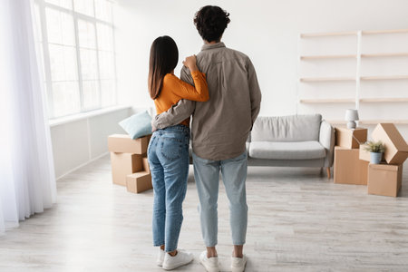 Millennial Couple Embraces in Their New Living Room on Moving Dayの写真素材