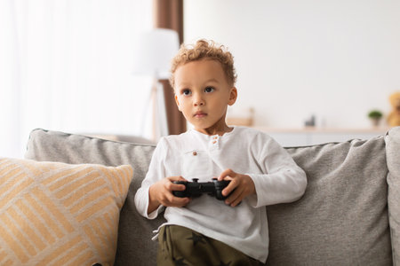 Cute African Little Boy Enjoys Video Games on Sofa at Home During Weekend Fun Time