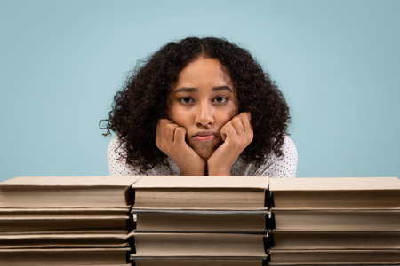 Young Black Student Feeling Exhausted While Studying in Blue Studio Backgroundの写真素材