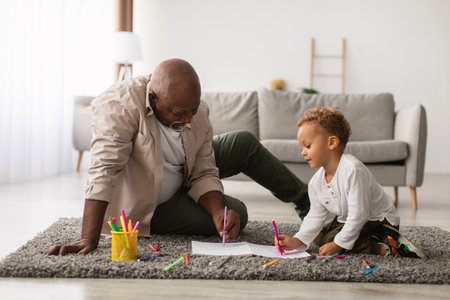 Happy Grandfather and Grandson Sketching Together on the Living Room Floor at Homeの写真素材