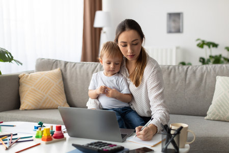 Mother Helps Her Child With a Computer Task While Seated Comfortably in a Cozy Living Room Spaceの写真素材