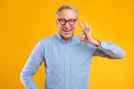 Happy Senior Man Showing Approval Gesture in Bright Studio Settingの写真素材