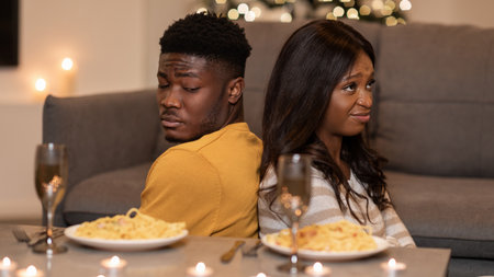 Displeased Couple Sitting Back-To-Back After Argument During Valentines Day Dinner at Homeの写真素材