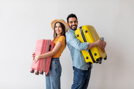 Couple Poses With Colorful Suitcases Ready for Their Travel Adventure in a Bright, Welcoming Spaceの写真素材