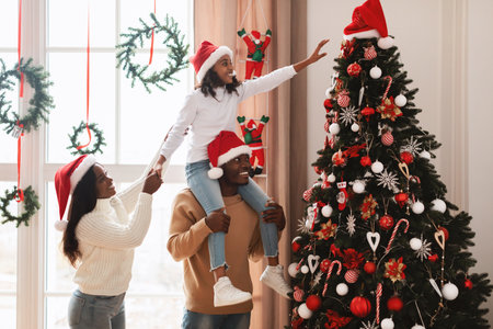 Happy Family Enjoys Decorating Christmas Tree Together in Cozy Living Roomの写真素材