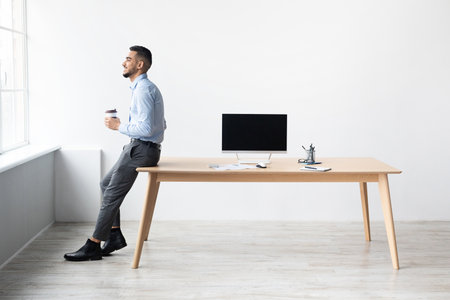 Successful Man Enjoying Coffee While Showcasing Laptop With Mockup Screen in Home Officeの写真素材