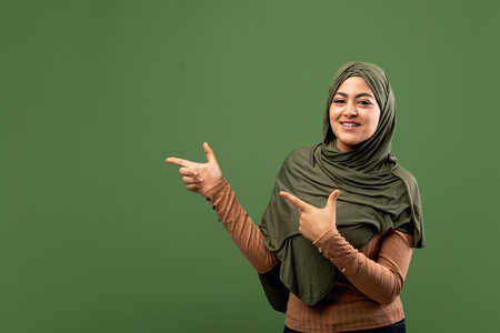 Excited Arab Woman in Hijab Pointing to Available Spaceの写真素材