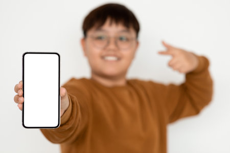 Cute Korean Teenager Showcases Modern Cellphone With Empty Screen in Bright Settingの写真素材